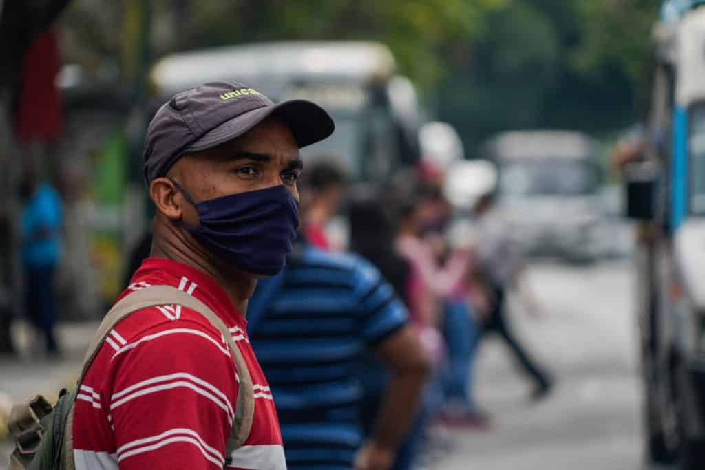 Un hombre con tapabocas esperando un transporte público sanciones en Sucre