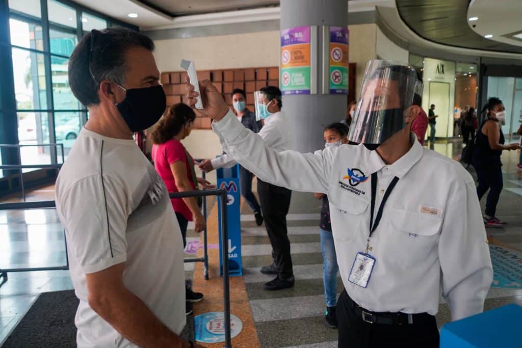 Persona de seguridad aplicando el termómetro electrónico en el centro comercial Sambil de Caracas