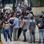 Personas haciendo cola en el banco BBVA Provincial en la semana de Persona secando pelo en una peluquería en la semana de flexibilización