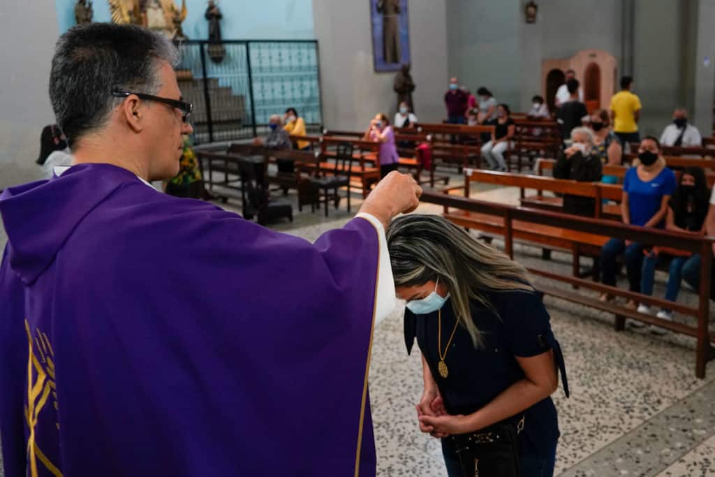 Padre aplicando las cenizas en el pelo en Iglesia de Nuestra Señora de Chiquinquirá en Miércoles de Ceniza
